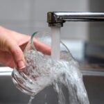 water spilling out of a glass to signify that tankless water heaters do not heat as much water