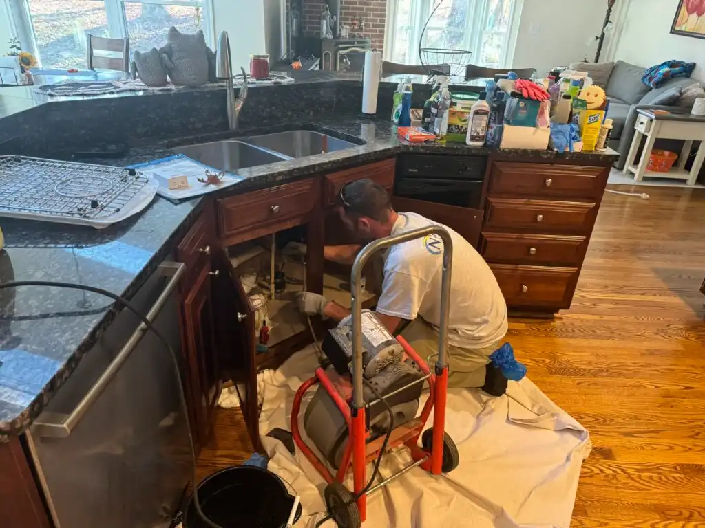 A Man Working In A Kitchen Doing Plumbing Service