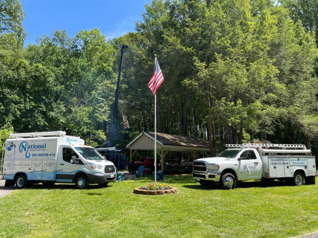 A White Truck And Van Parked In A Grassy Area With A Flag Pole