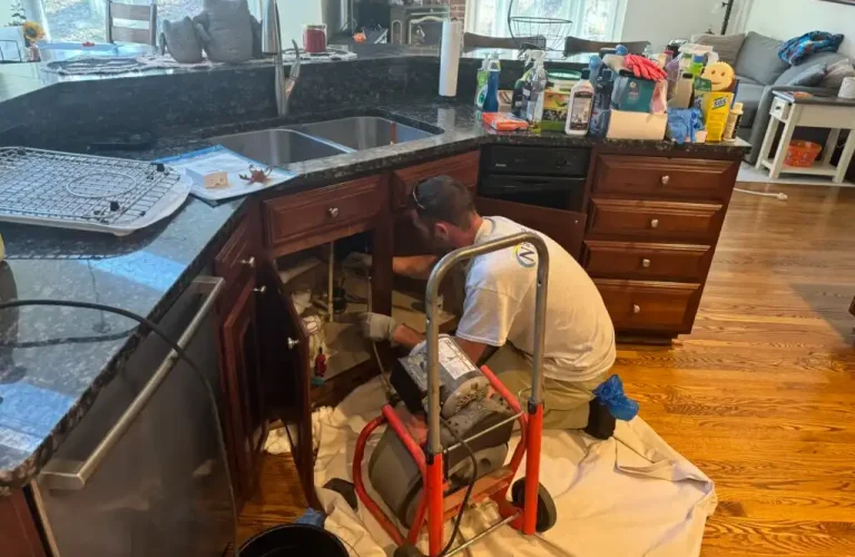 A Man Working In A Kitchen Doing Plumbing Service