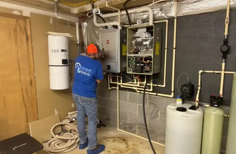 A Man Working On A Tankless Water Heater By National Water Service